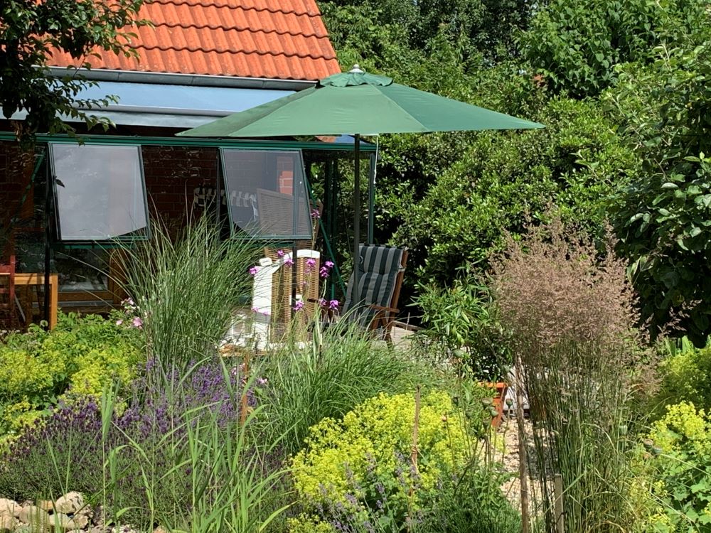 Die Terrasse mit Sonnenschirm und Gartenstühlen